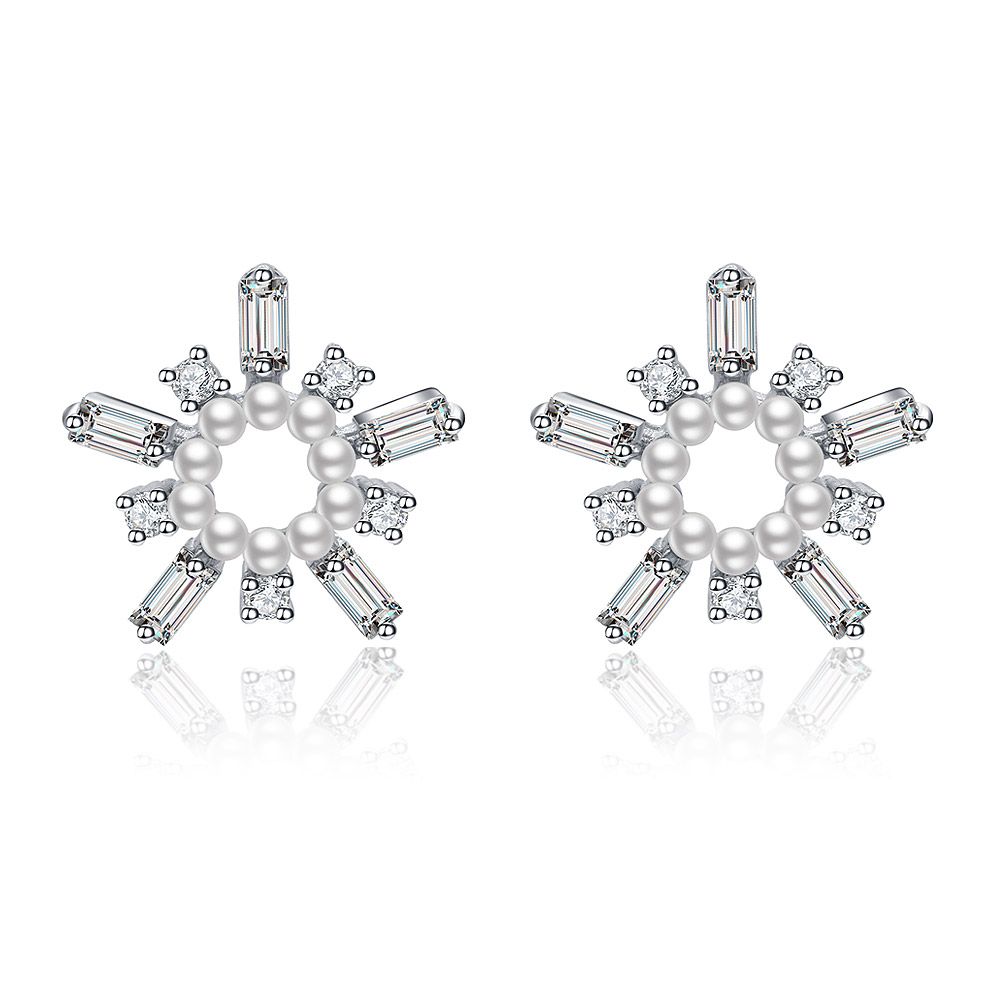 A close-up of the White As Snow Pearl Earrings, showcasing the intricate snowflake design with a central white pearl and sparkling cubic zirconia stones on a white background.