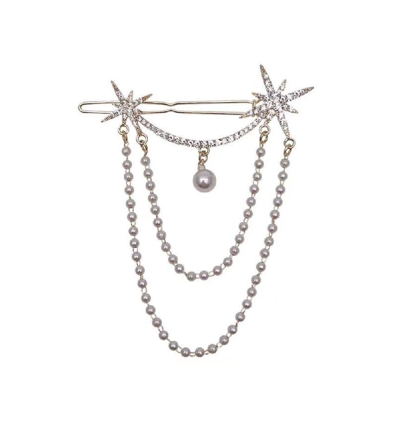 Un primer plano del pasador de cabello colgante con forma de estrella, un accesorio temático celestial chapado en oro con motivos de estrellas y acentos de perlas.