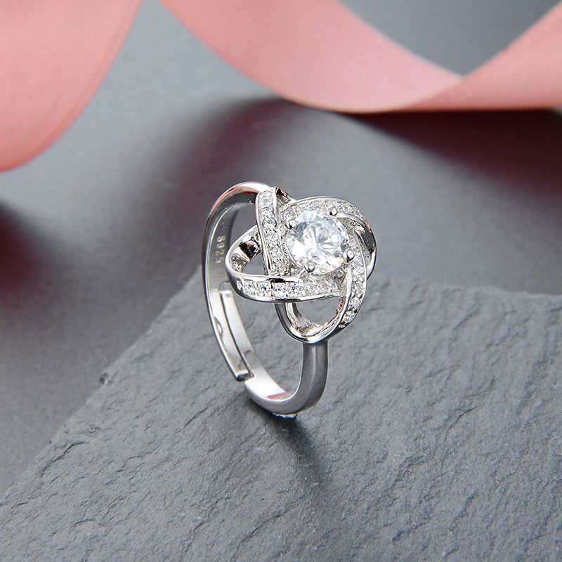 Un primo piano di un anello regolabile in argento sterling 925 con design a trifoglio vuoto e una pietra preziosa centrale trasparente, parte di un set di 5.