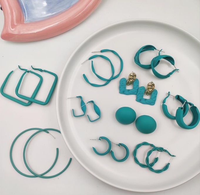 A vibrant collection of blue and teal enamel earrings from JR Fashion Accessories' Summer 2022 line, displayed on a white surface.