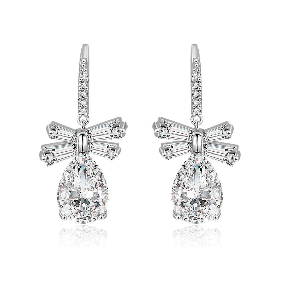 Vooraanzicht van de Witte CZ Ovale Dangle Strik Oorbellen, met een grote druppelvormige cubic zirconia steen gezet in rhodium-geplateerd messing met een delicate strikdetail.