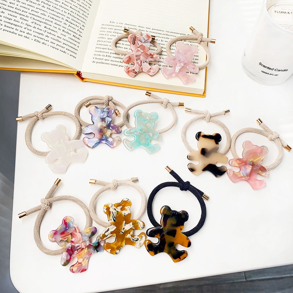 A collection of colorful elastic hair tie bands, each adorned with a unique bear-shaped charm made from acetate, displayed on a neutral background.