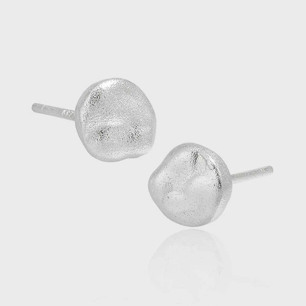 Een paar minimalistische ronde stud oorbellen van 925 sterling zilver, één in 18K goudplaat en één in zilver, tentoongesteld op een gestructureerd oppervlak om hun eenvoudige, elegante ontwerp te tonen.