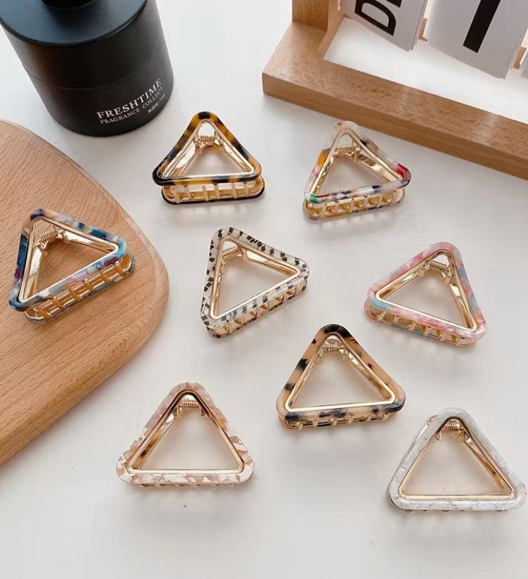 Uma coleção vibrante de clipes de cabelo triangulares por atacado em várias cores e padrões elegantes, oferecida por JR Fashion Accessories.