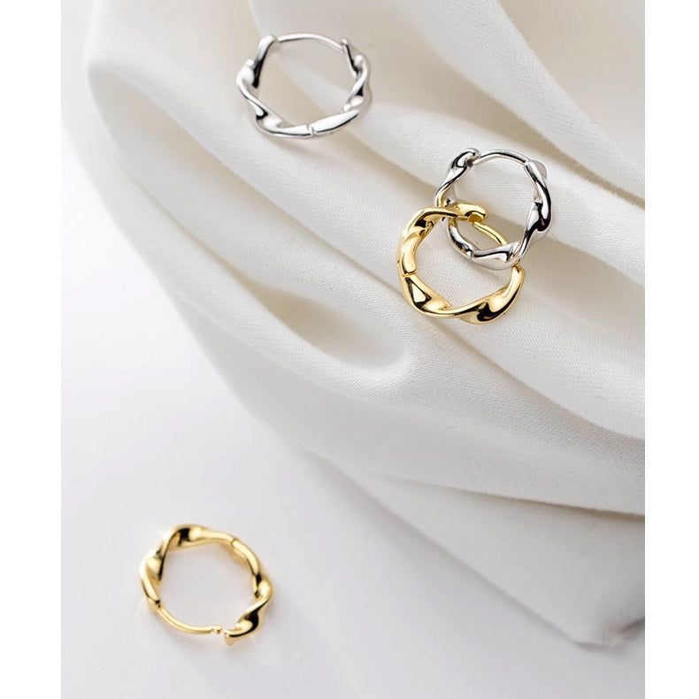 Un paio di orecchini a cerchio intrecciati in argento sterling 925 mostrati sia nella elegante finitura argento che in quella classica oro.