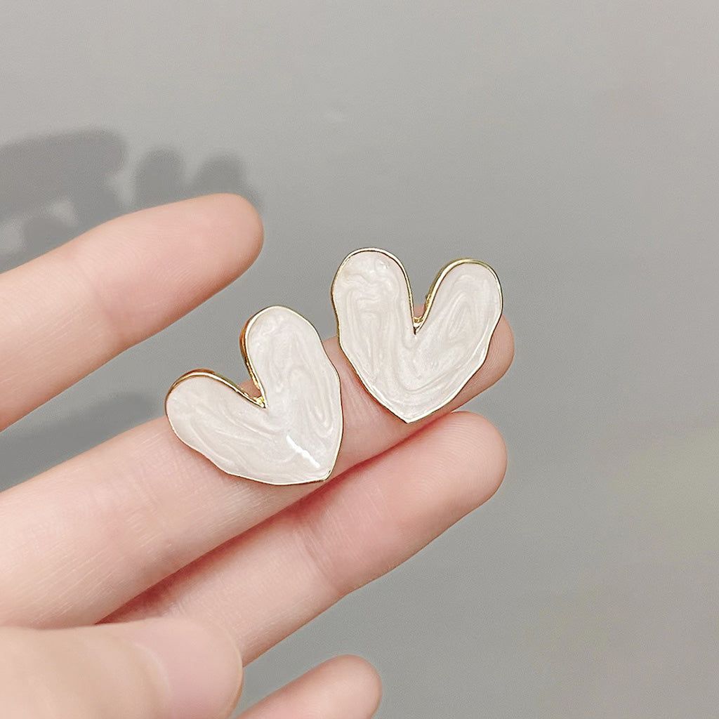 A pair of sweet white enamel geometric heart stud earrings with elegant gold trim, displayed on a clean background.