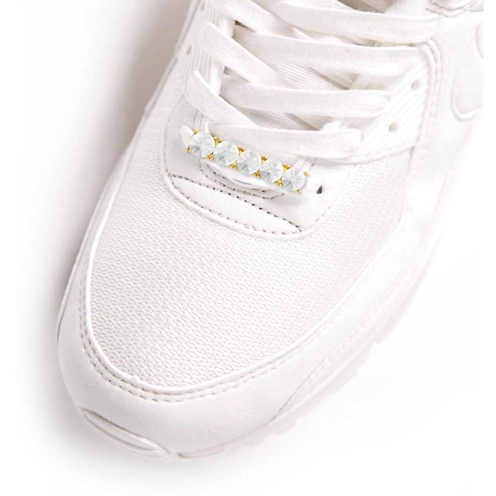 Una zapatilla blanca elegante que presenta la etiqueta de zapato de cristal brillante con gemas claras entrelazadas en los cordones.