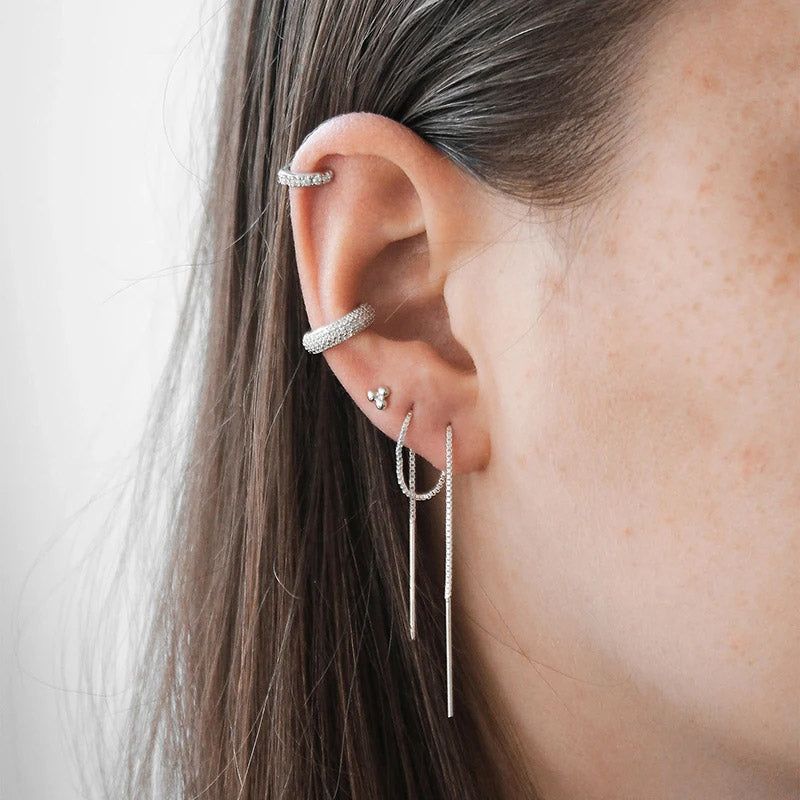 L'orecchio di una donna adornato con un elegante set di orecchini a cerchio in zirconia senza piercing in argento sterling 925, che mostra un look impilato.