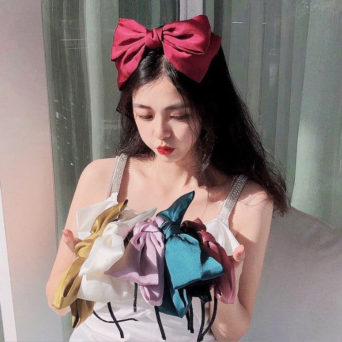 Las manos de una mujer sosteniendo una vibrante colección de diademas de gran lazo de estilo vintage para niñas, disponibles en múltiples colores.