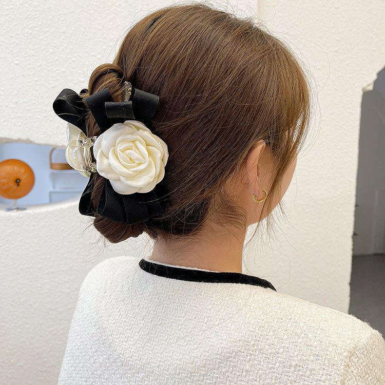 A model showcasing the elegant white camellia flower and black ribbon hair claw clips in a stylish bun hairstyle.