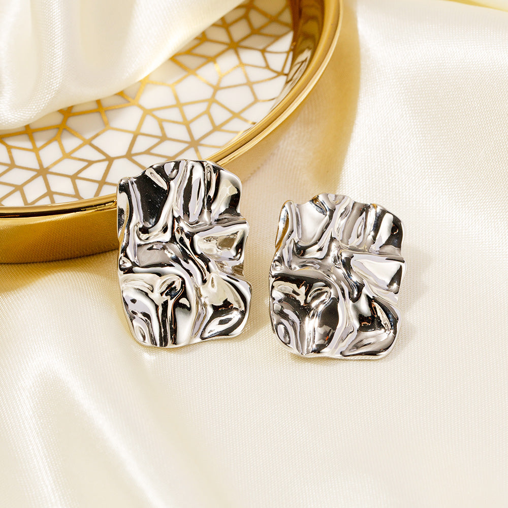 A pair of stainless steel chunky rectangle stud earrings with a textured, abstract design in a silver finish.