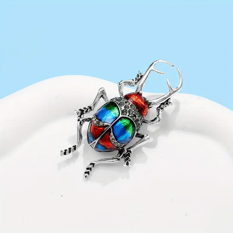 Front view of the 3D beetle bug brooch, showcasing its intricate enamel work, silver plating, and sparkling rhinestone details.