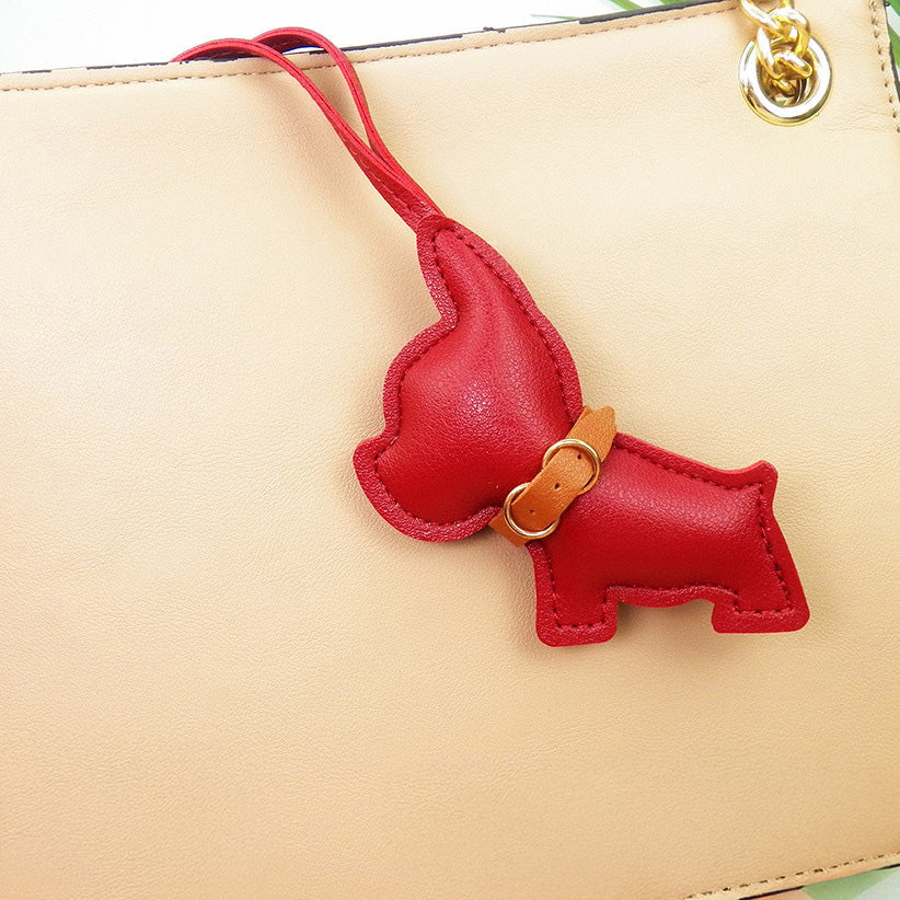 A stylish beige leather bag accessorized with a vibrant red PU leather French Bulldog charm.