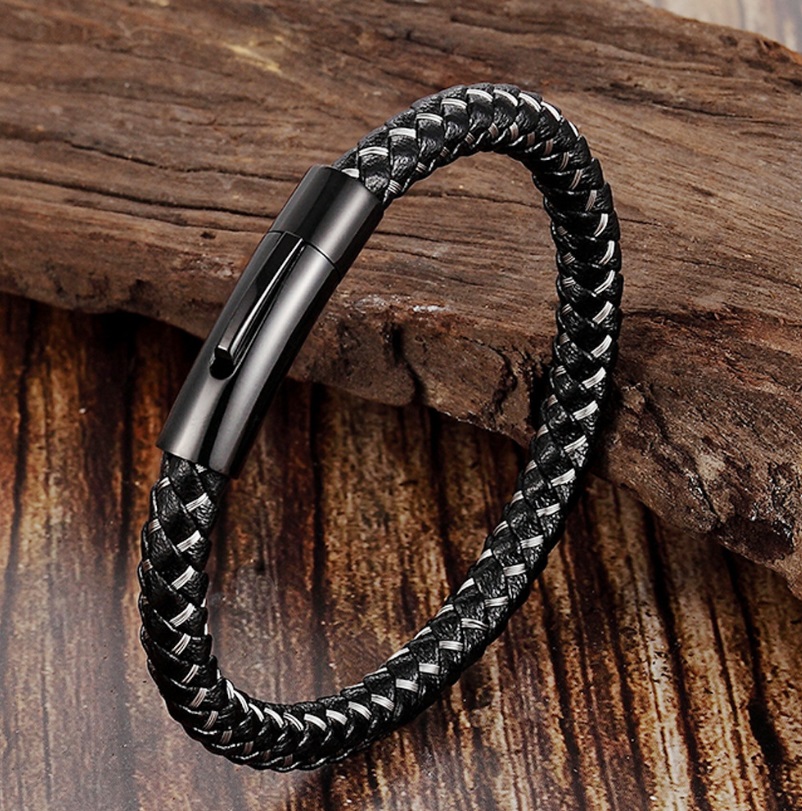 Close-up of a stylish black braided genuine leather men's bracelet with a durable stainless steel clasp, displayed on a rustic wooden surface.