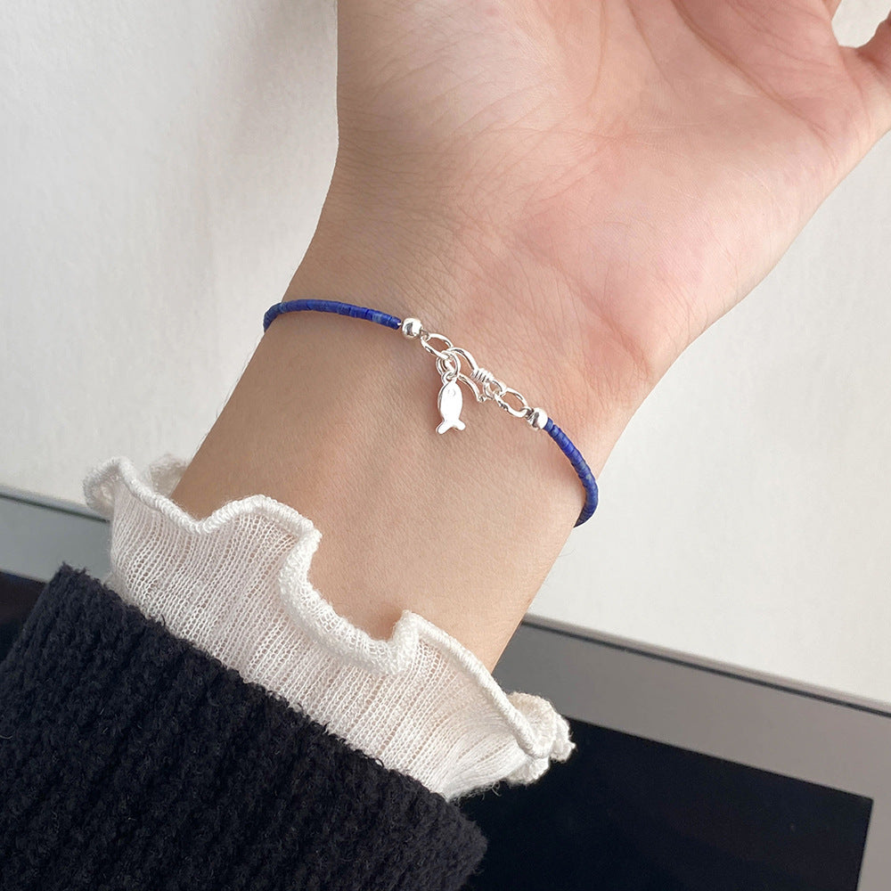 Model wearing a minimalist 925 sterling silver lapis lazuli bracelet with a delicate fish charm, perfect for wholesale jewelry collections.