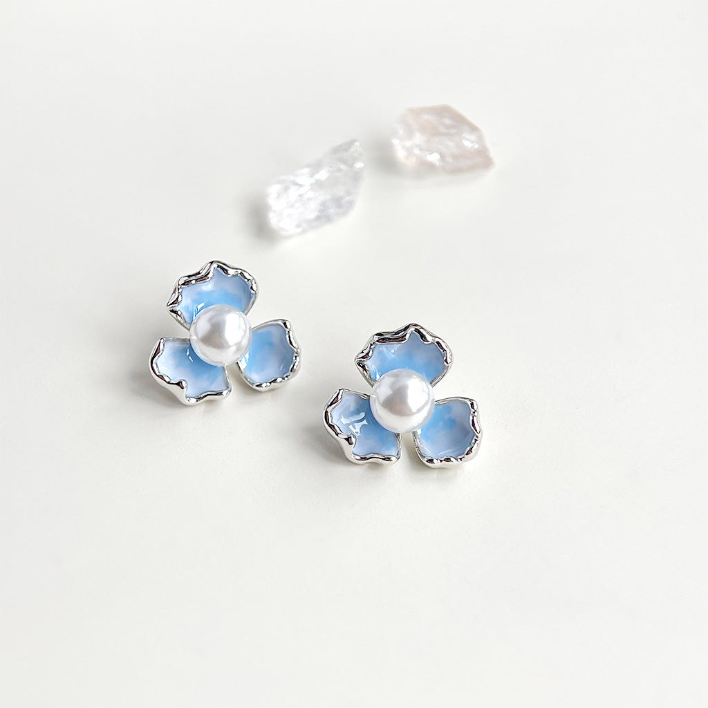 A pair of wholesale silver-plated iris flower stud earrings with gradient blue enamel petals and a central pearl.