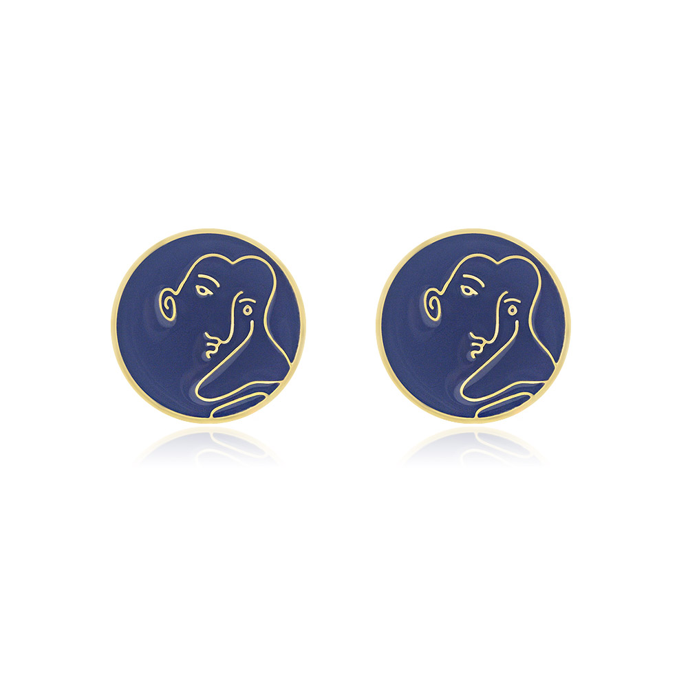 A pair of round, gold-plated stud earrings featuring a unique purple enamel face with an artistic line drawing of a woman's profile. The design is modern and elegant.