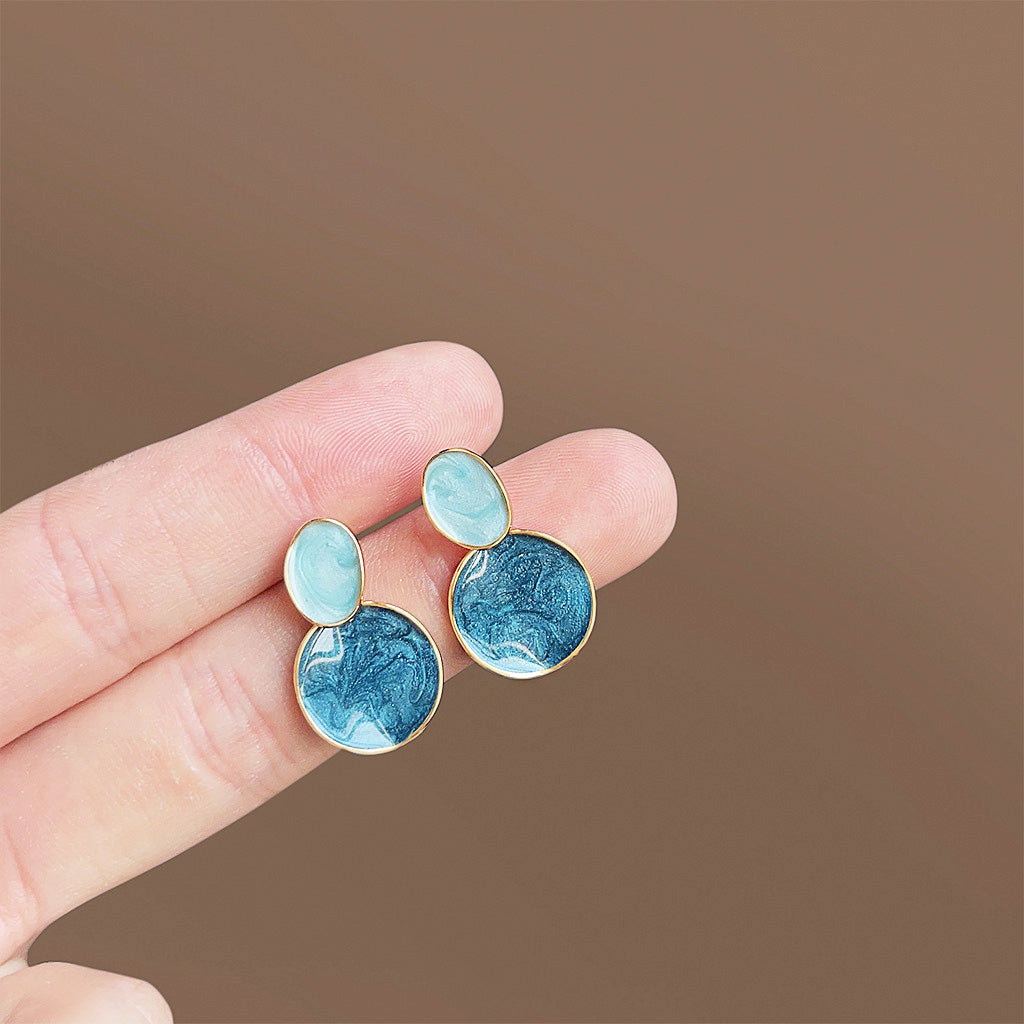 A pair of wholesale 14k gold-plated drop dangle earrings featuring a unique blue marbled enamel stone set in a polished gold brass frame.