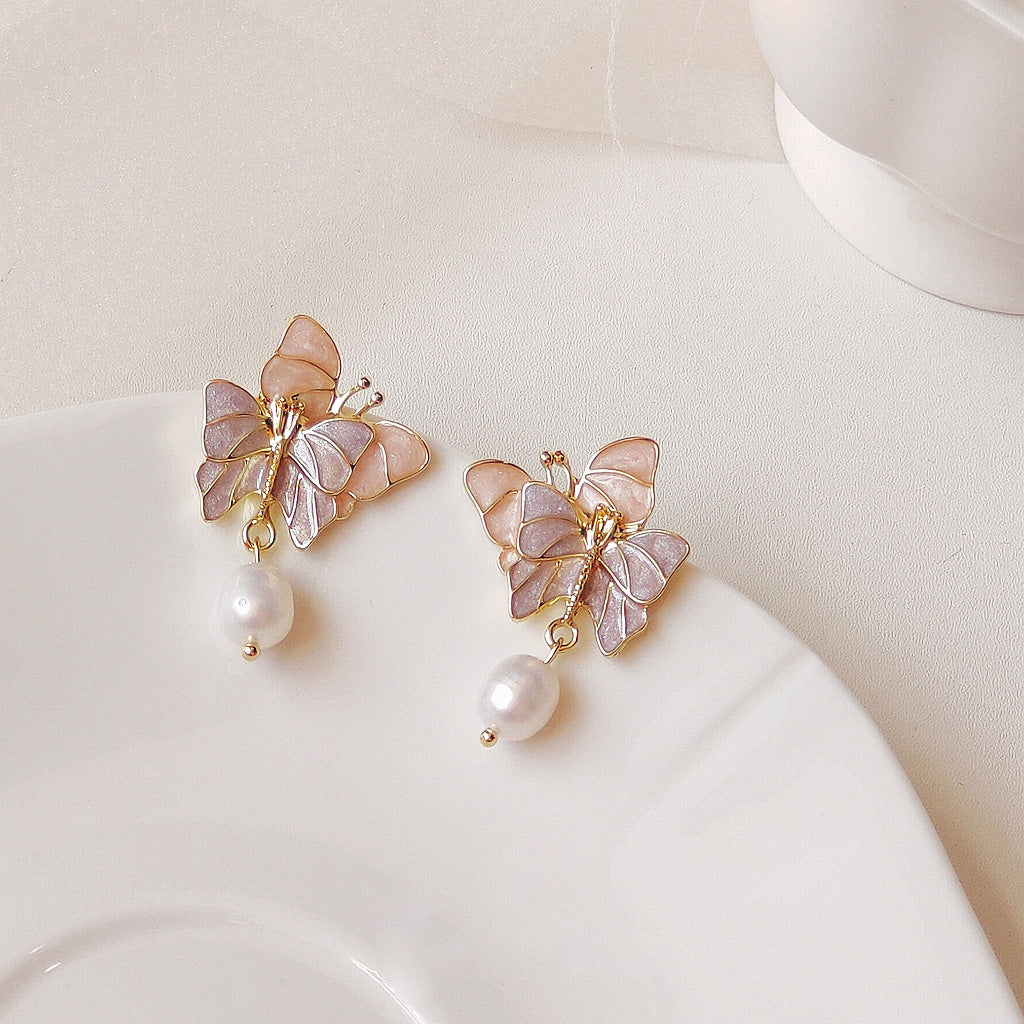 A pair of 14k gold plated enamel double butterfly earrings with delicate freshwater pearl drops, shown against a clean white background.