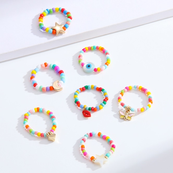 A vibrant collection of colorful beaded rings and bracelets with assorted charms, showcasing the customizable style of JR Fashion Accessories' beaded jewelry.
