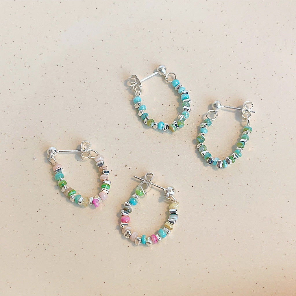A set of three pairs of silver-plated hoop earrings adorned with vibrant, multi-colored beads, displayed on a clean white background.