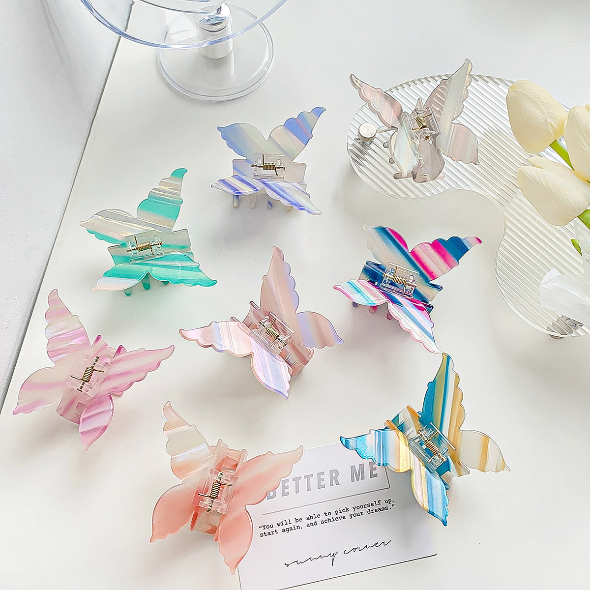 A vibrant set of women's butterfly hair claw clips made from colorful strip-patterned acetate.