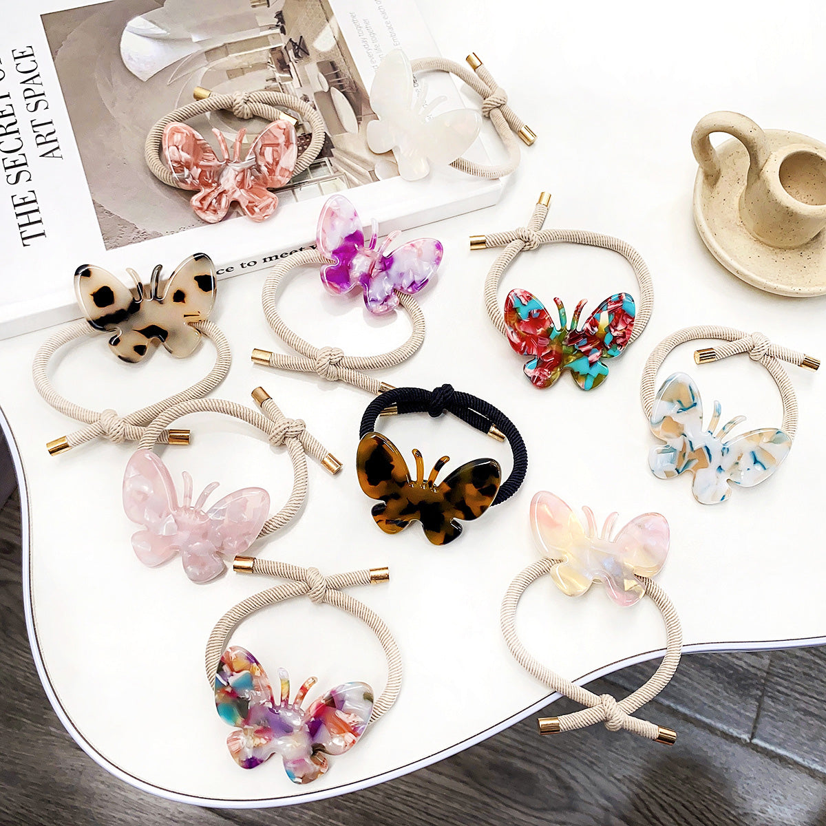 A vibrant collection of butterfly-shaped acetate hair ties in various marbled colors, perfect for ponytails and stylish updos.