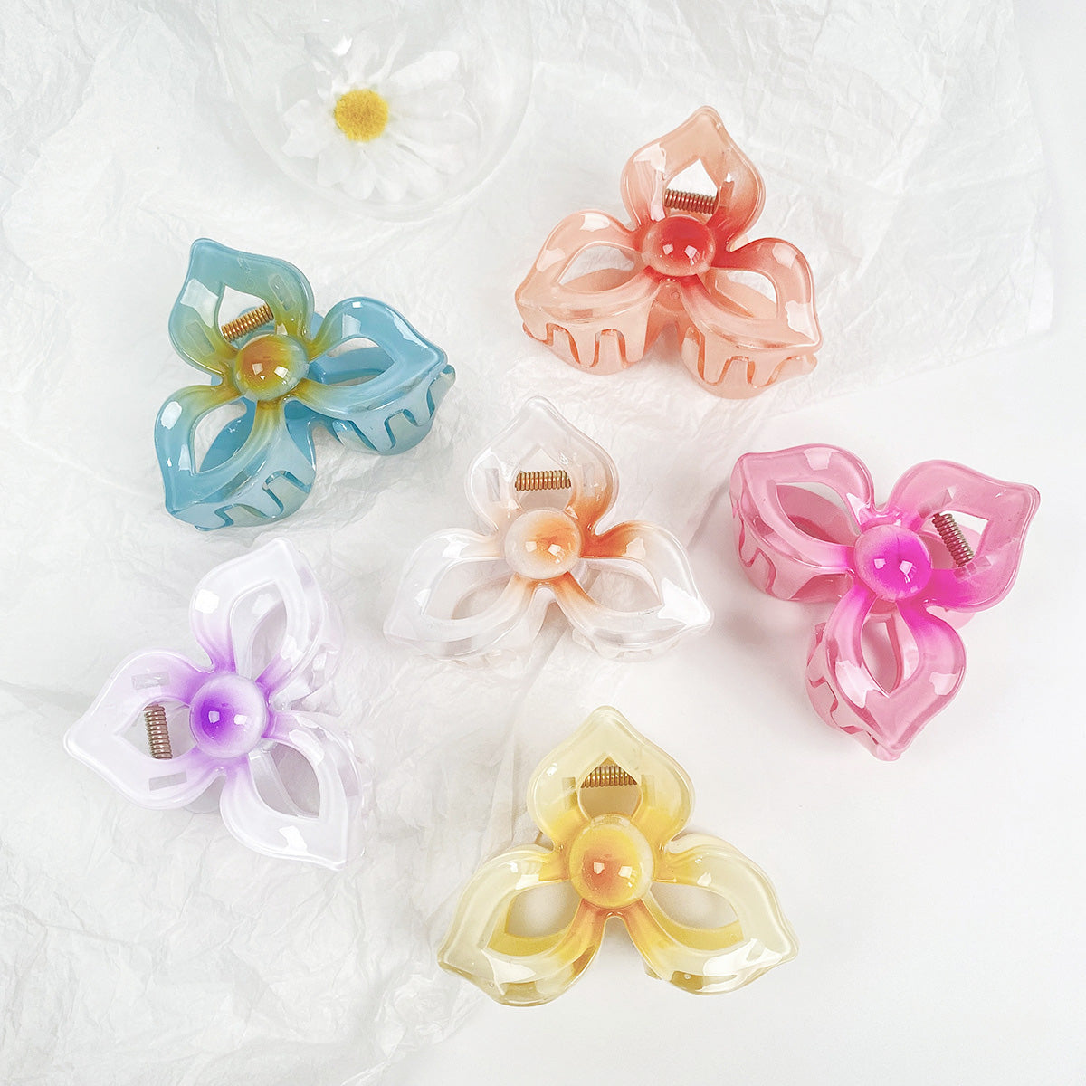 A collection of six large 8cm frangipani (plumeria) flower hair claw clips in various vibrant colors, arranged on a white background.