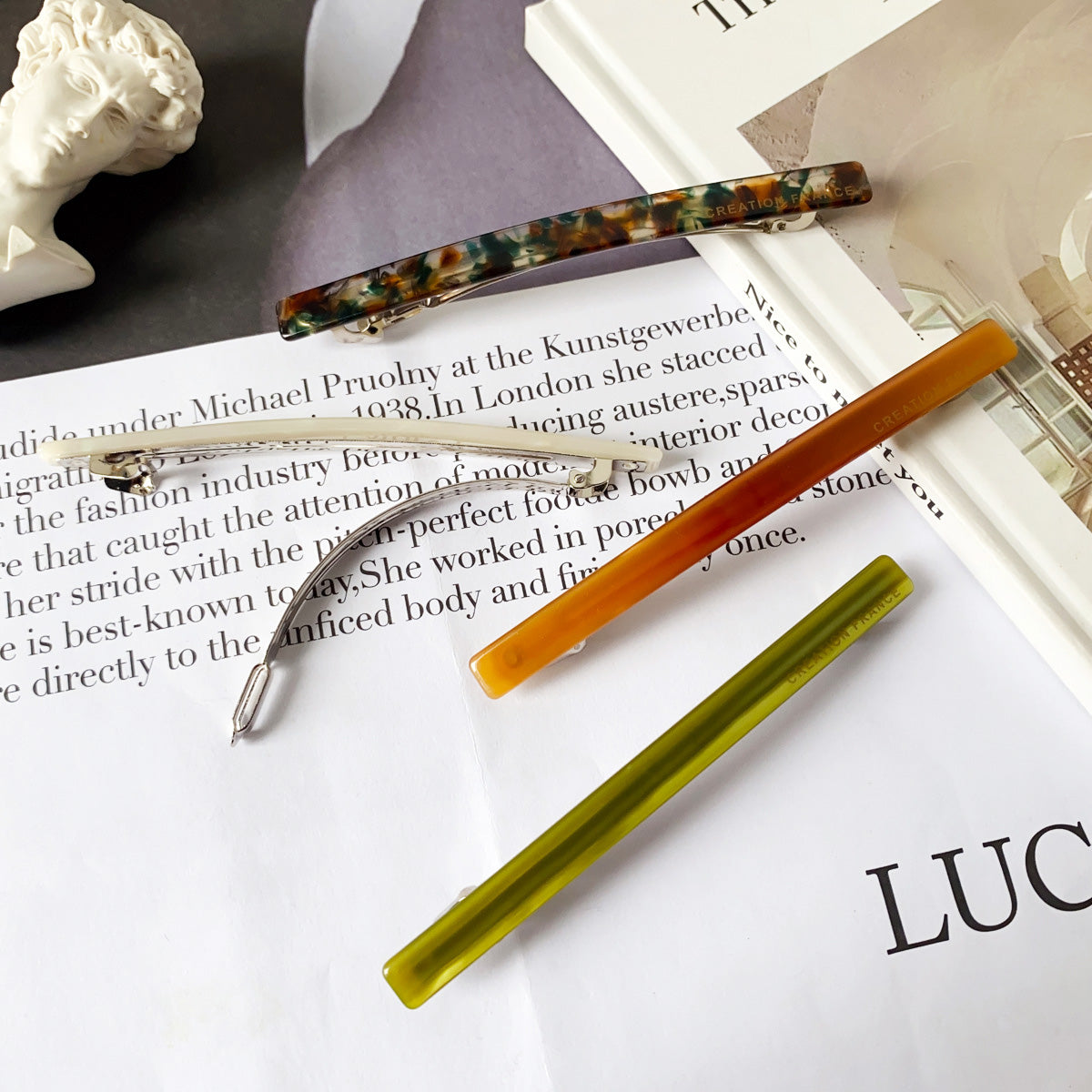 A vibrant collection of long acetate stick hair barrette clips in various colors, stylishly arranged for a product showcase.