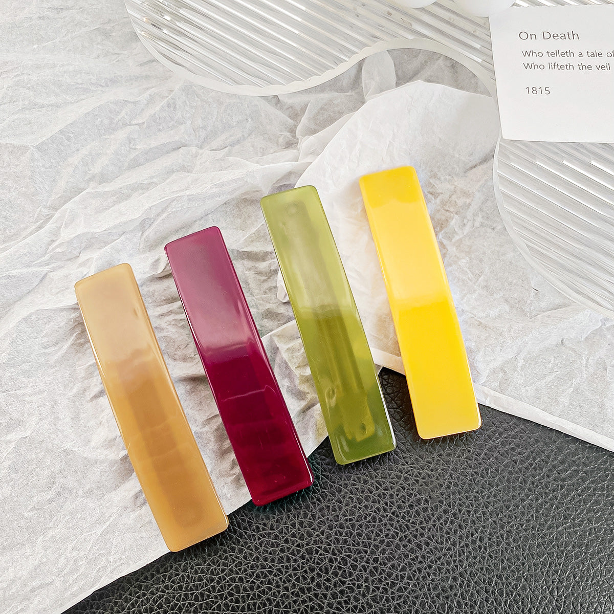 A set of four solid color rectangle hair barrette clips in yellow, green, brown, and red, displayed neatly for product showcase.