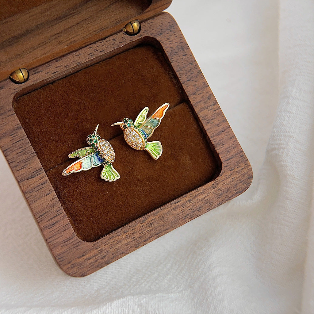A set of five pairs of 14k gold-plated enamel bee and bird stud earrings with colorful zircon stones, displayed in a wooden box.