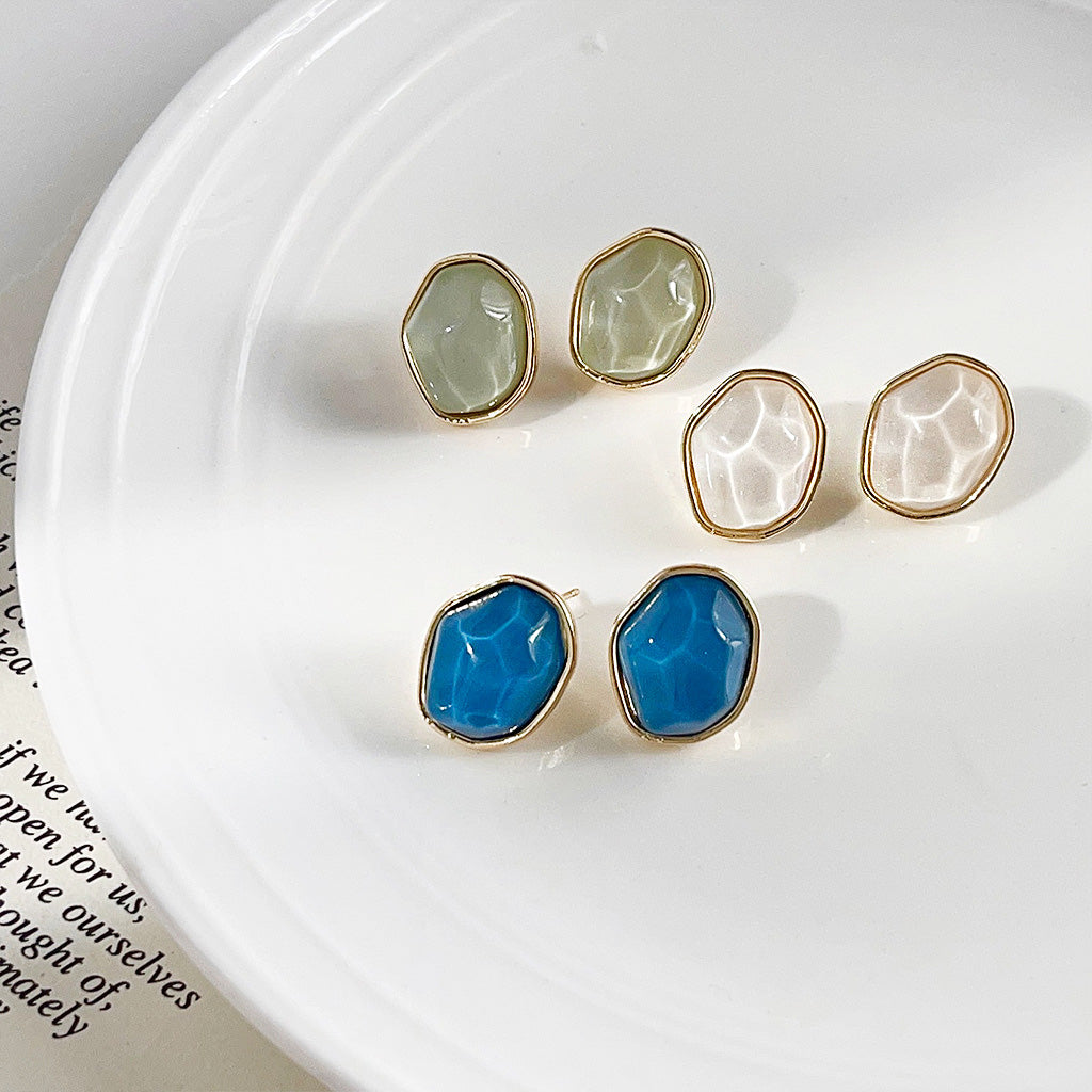 A set of three pairs of 14K gold plated irregular geometric stud earrings in blue, white, and green resin, displayed together.