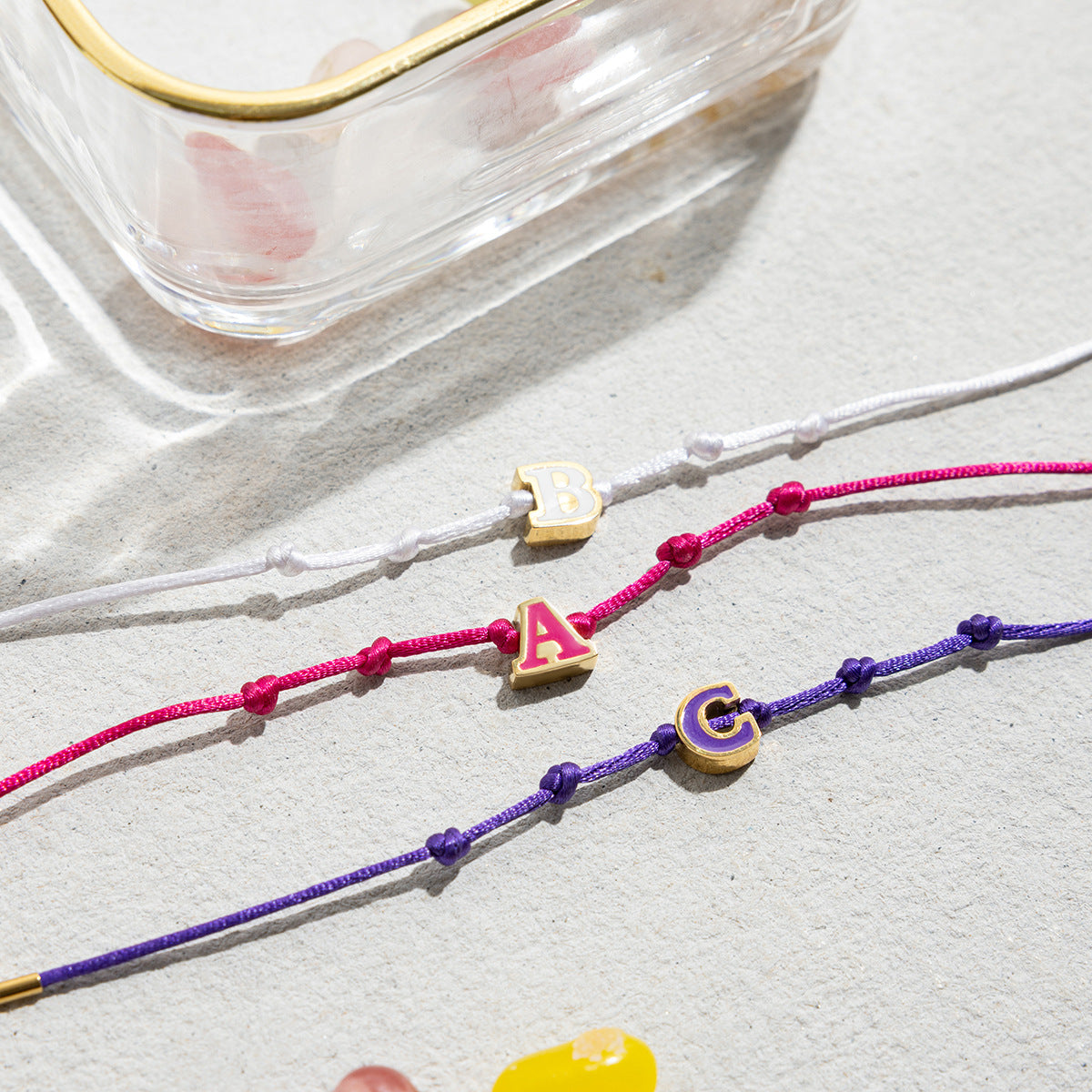 A vibrant collection of 18K gold-plated stainless steel friendship bracelets featuring colorful enamel initial charms 'A', 'B', and 'C', perfect for wholesale and personalized jewelry.