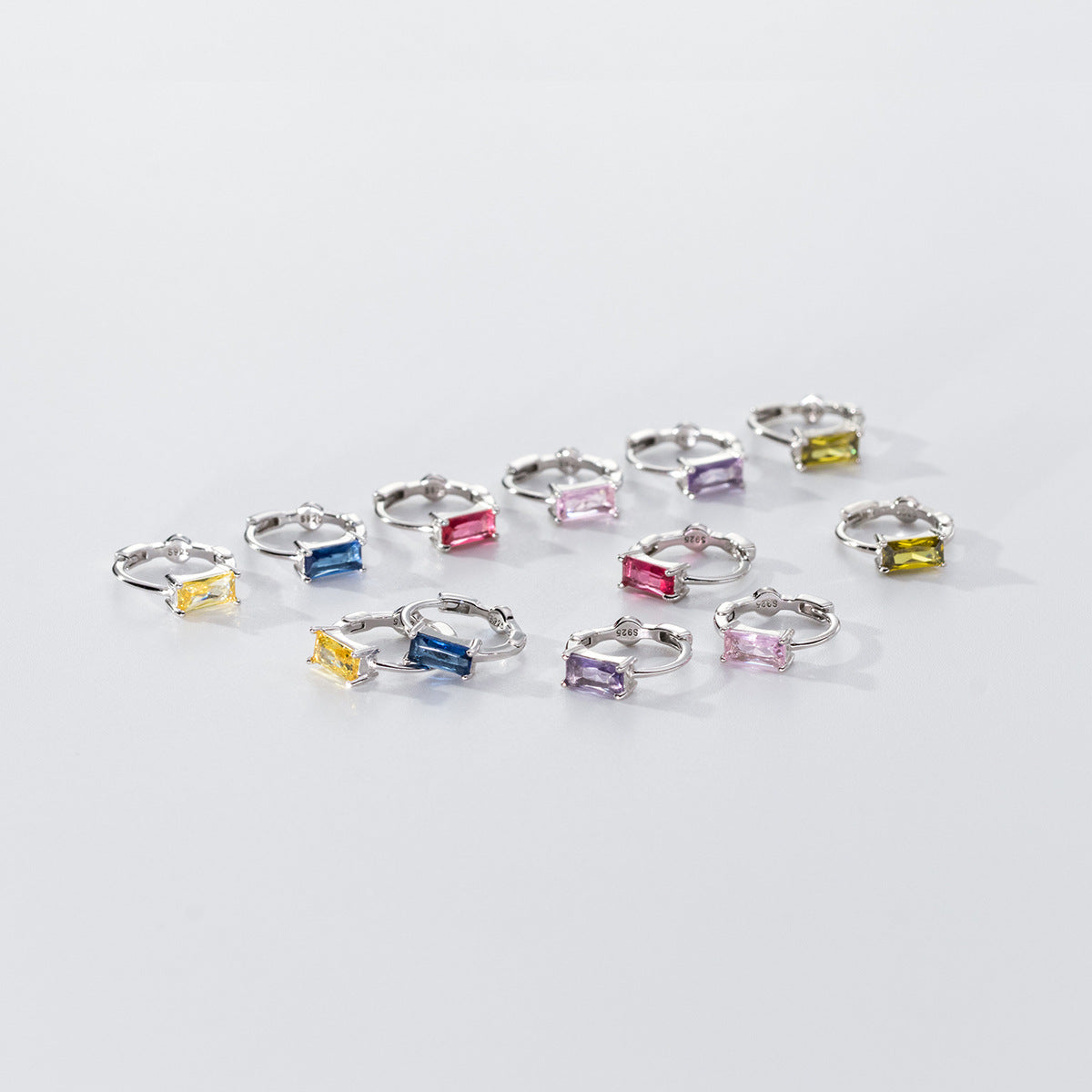 A collection of 925 sterling silver huggie hoop earrings showcasing a variety of colorful square-cut zircon gemstones, displayed on a clean white background.