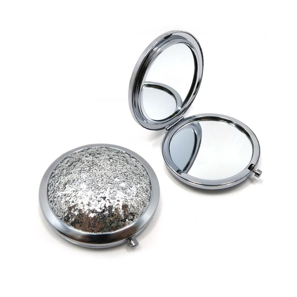 A stylish round compact cosmetic mirror with a sparkling silver sequin 3D lid, shown open and closed.
