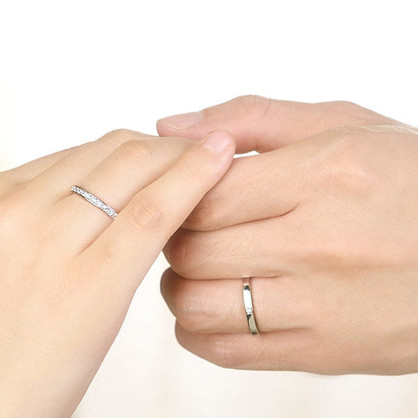 A close-up of a couple's hands, showcasing the elegant 925 sterling silver and cubic zirconia matching ring set.