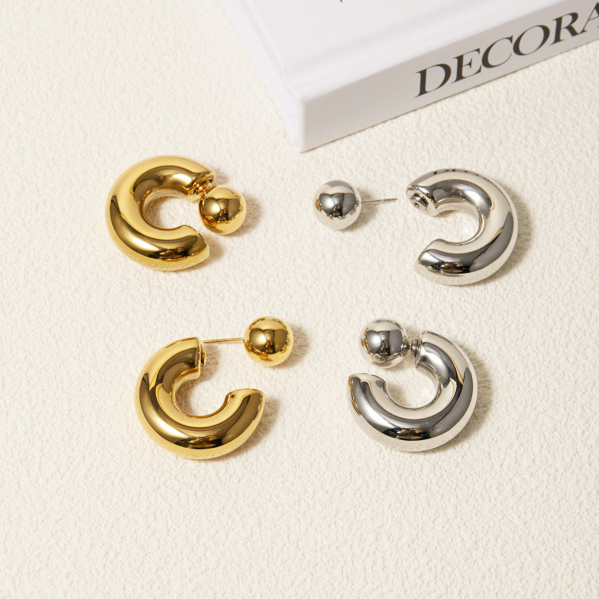 A set of stainless steel chunky ball stud earrings, displaying two pairs in a gold finish and two pairs in a silver finish, arranged neatly on a neutral background.