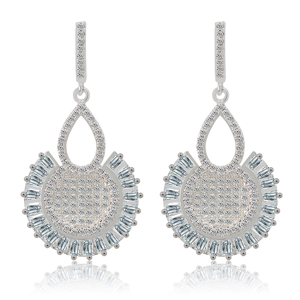 A pair of Till Daylight Earrings, featuring a teardrop top and a circular pendant with cubic zirconia stones, set in rhodium-plated brass.
