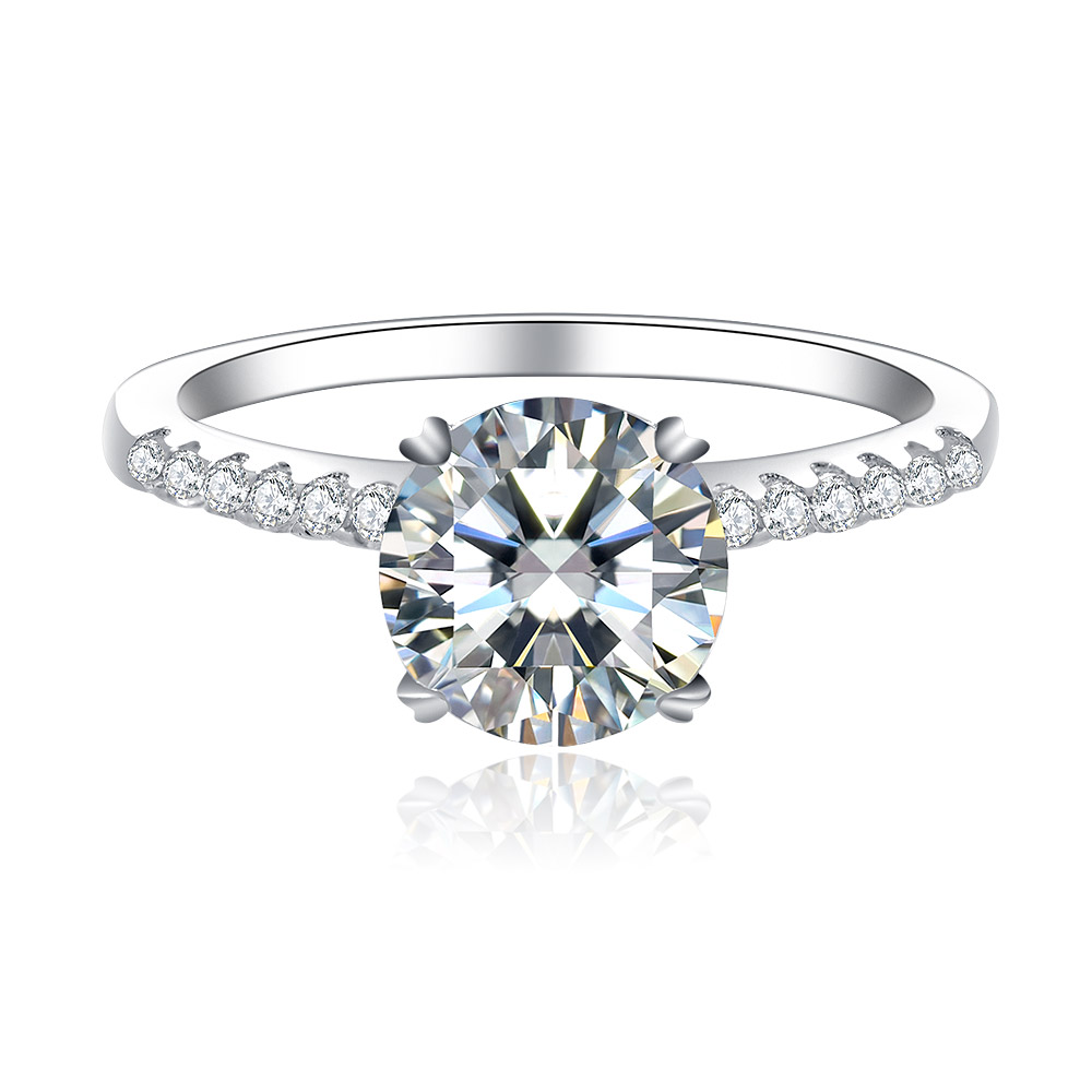 A stunning Round CZ Engagement Ring featuring a large round-cut cubic zirconia centerpiece in a four-prong setting on a rhodium-plated brass band with side stone accents.