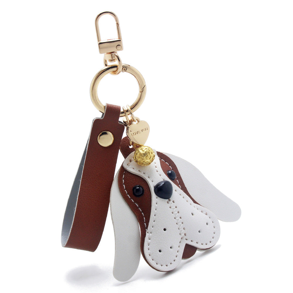 A cute wholesale dog keychain made of brown and white PU leather, featuring a 3D puppy face with gold-tone hardware, perfect as a bag charm.
