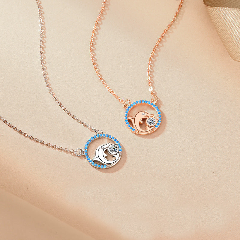 A pair of 925 sterling silver dolphin pendant necklaces, one in a silver finish and the other in rose gold, both adorned with delicate blue gemstones.