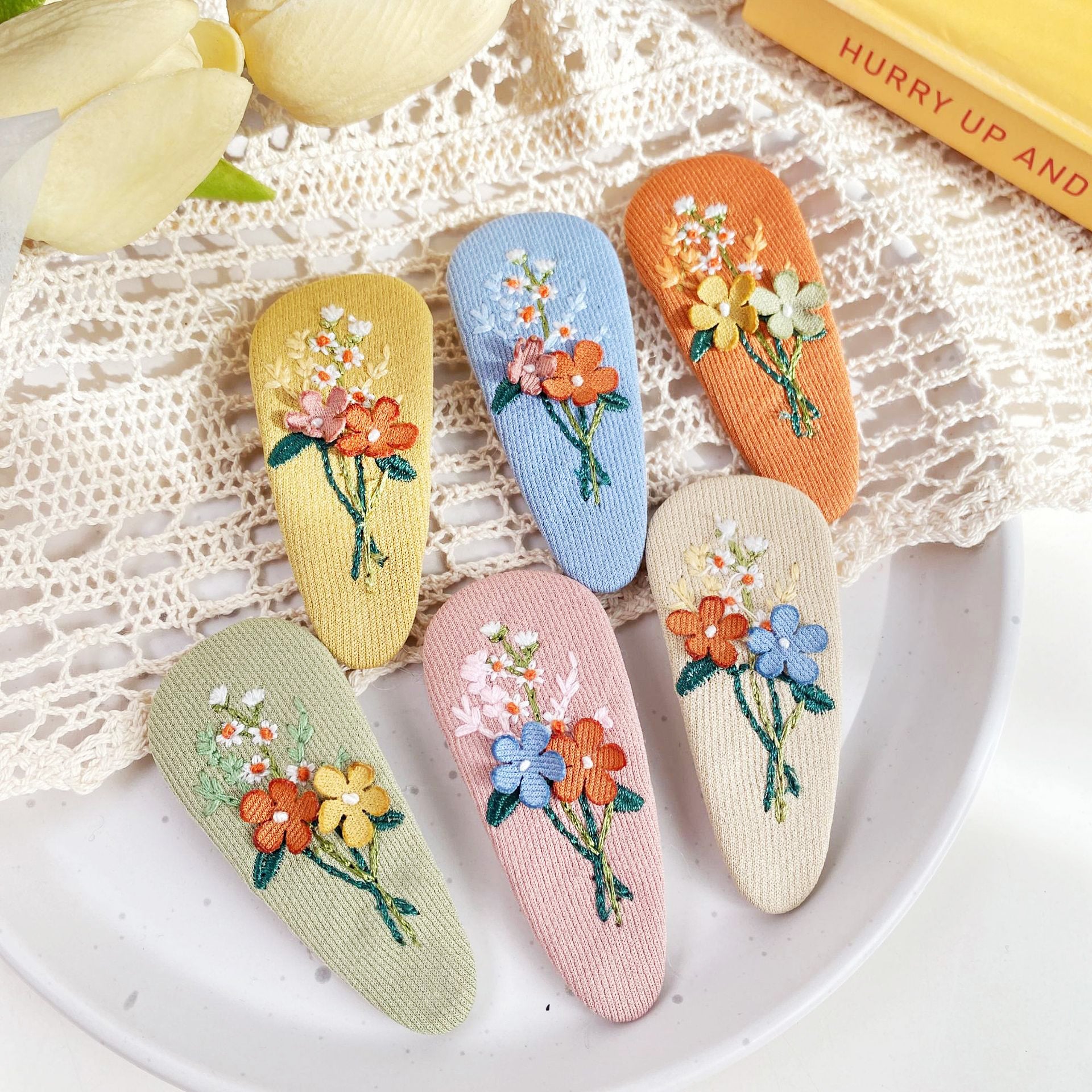 A collection of colorful fabric embroidered floral hair snap clips for girls, displayed on a clean white background.