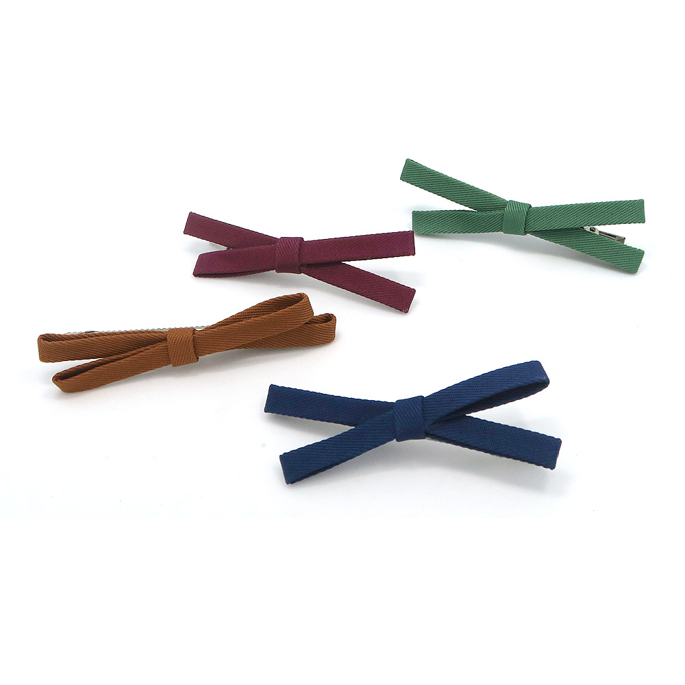 A collection of four trendy fabric hair side pins in assorted colors, neatly arranged to showcase the product variety.