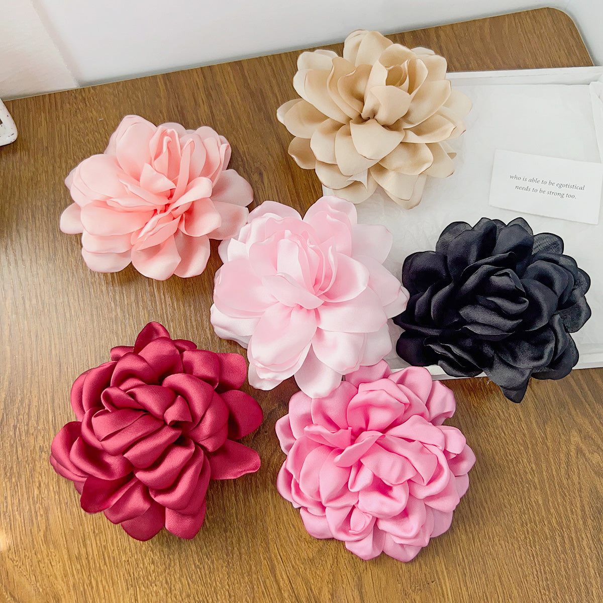 A vibrant collection of big rose flower side hair clips in multiple colors, including pink, red, and black, available for wholesale.