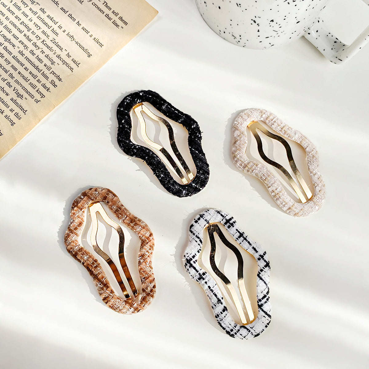 A set of four stylish cloud-shaped snap hair clips for girls, shown in various neutral colors with gold metal interiors.