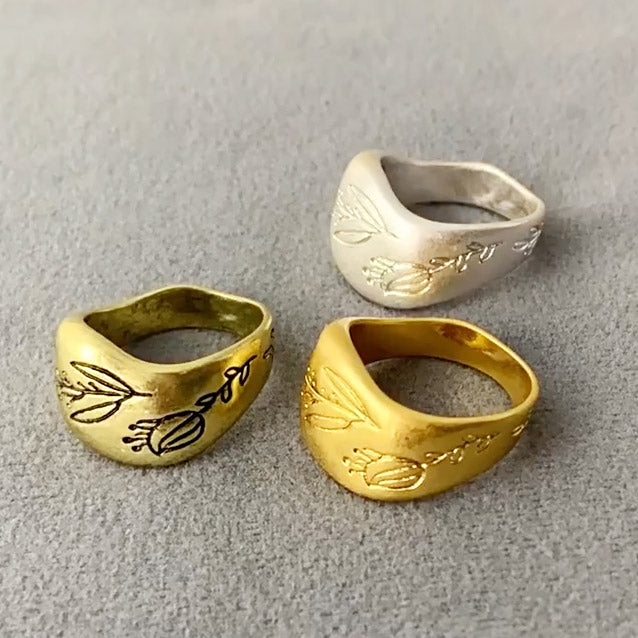A set of three brass chunky band rings with intricate plant-pattern engravings, displayed on a neutral background.