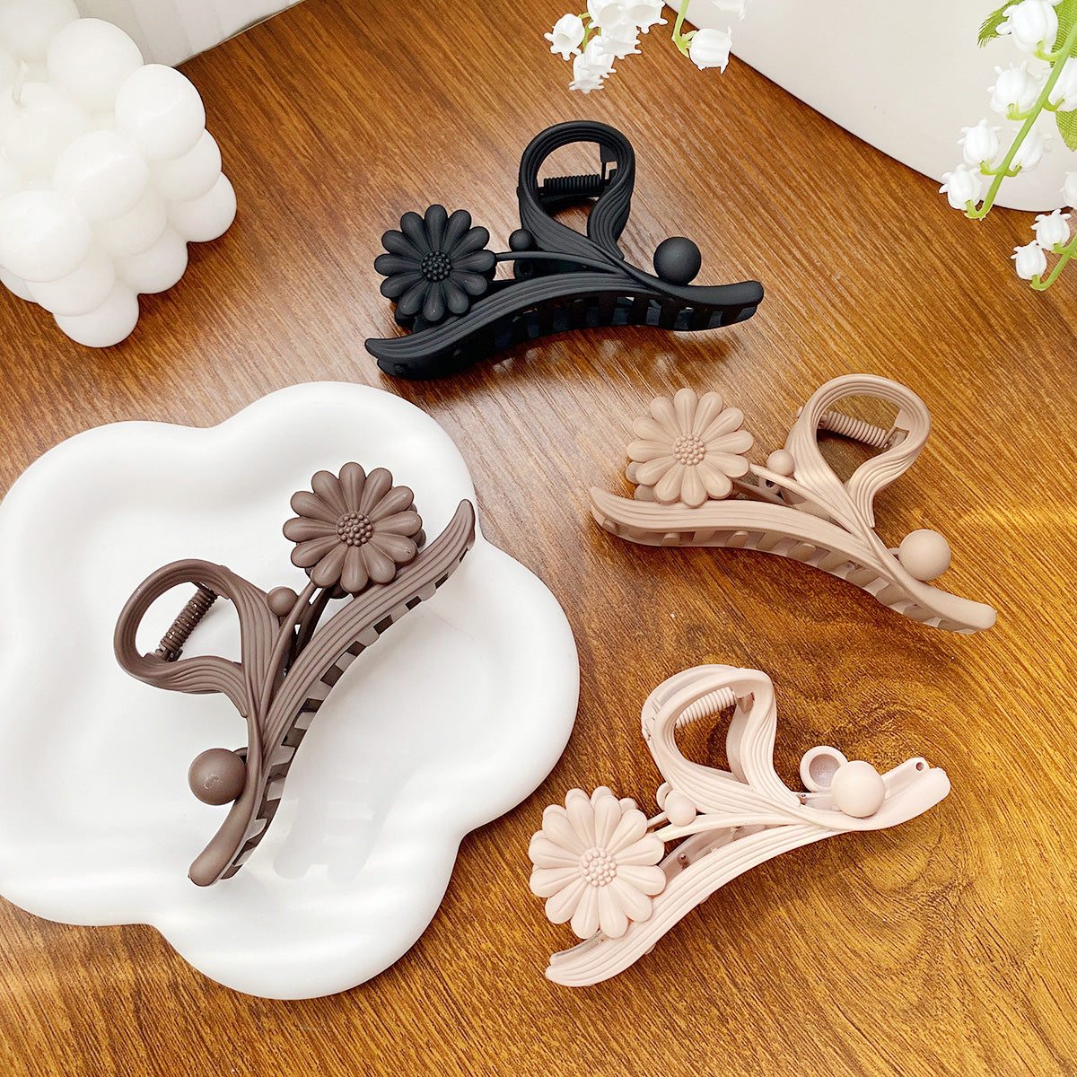 A set of four daisy flower hair claw clips in assorted colors: pink, brown, walnut, and black, displayed on a white background.