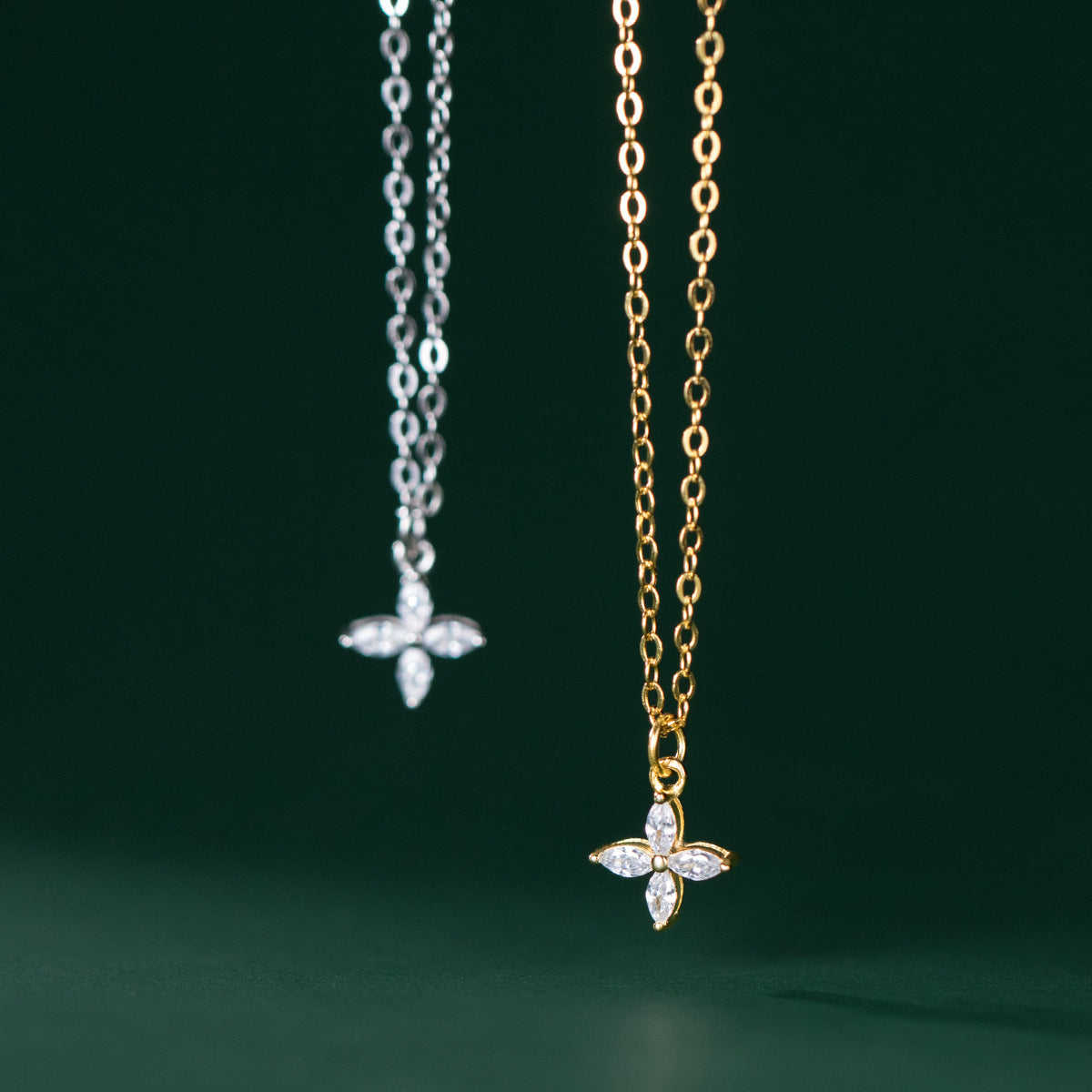 A pair of 925 sterling silver four-leaf clover flower necklaces, one in a polished silver finish and the other in a radiant gold finish, both featuring delicate gemstone details.