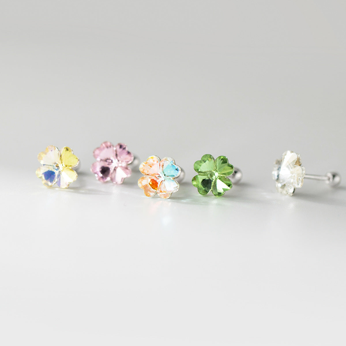 A vibrant collection of five pairs of wholesale 925 sterling silver four-leaf clover stud earrings with colorful crystal gemstones, displayed on a clean white background.
