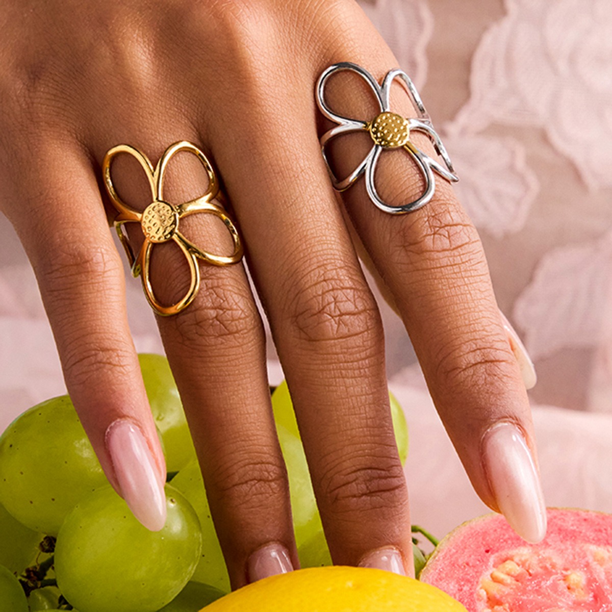 A hand model wearing the adjustable stainless steel daisy rings in both gold and silver finishes, part of a wholesale set of five.